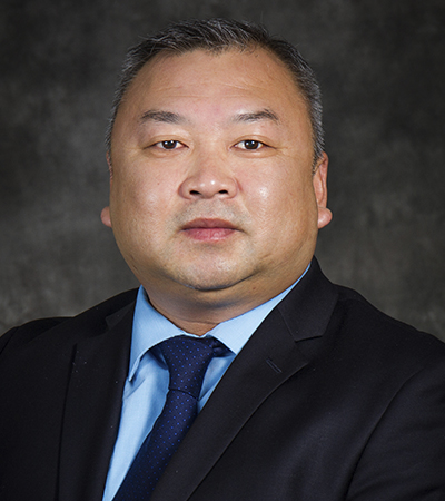 Man with short salt and pepper hair wearing a suit and tie