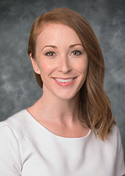 Woman with brown, shoulder length hair wearing a white blouse