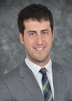 Man wearing a grey suit with grey, blue and orange tie