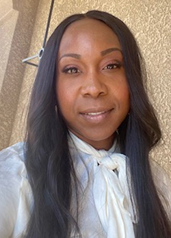 Woman with long straight black hair wearing a white blouse with white scarf