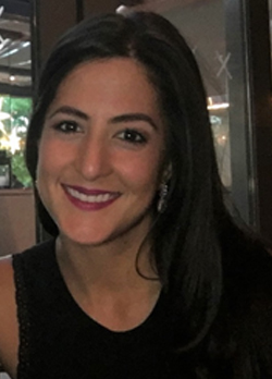 Woman with long black hair wearing a black sleeveless shirt sitting in a restaurant