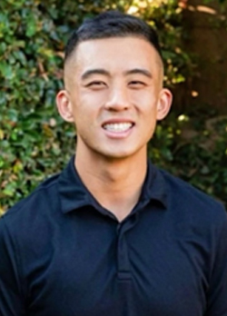 Man with short black hair wearing a navy polo