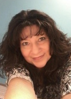 Woman with brown hair wearing a patterned blouse