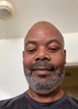 Man with bald head and trimmed beard wearing a black t-shirt