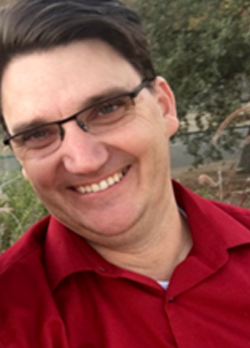 Man with brown hair wearting glasses and a red polo