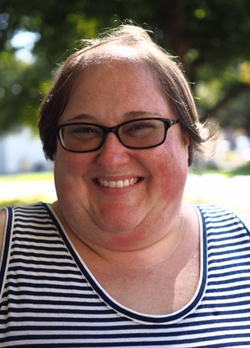 Woman with short brown hair wearing glasses and a white and blue striped tank top