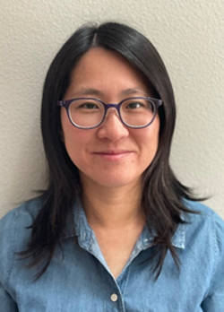 Woman with medium length straight hair wearing prescription glasses and a denim button up shirt