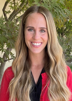 Woman with long blonde hair wearing a red sweater over black blouse