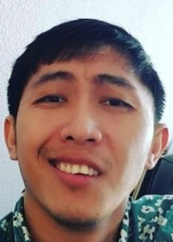 Man with short black hair wearing a green shirt with a pattern of white flowers