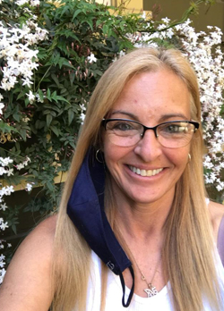 Woman with blonde hair wearing precription glasses and a white tank top