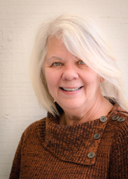 Woman with white hair wearing an orange sweater