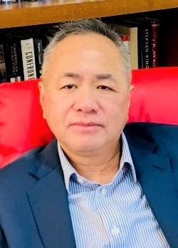 Man with short salt and pepper hair wearing a navy sportcoat over blue and white striped dress shirt