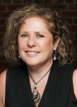 Woman with short, curly brown hair wearing a black, v-neck blouse