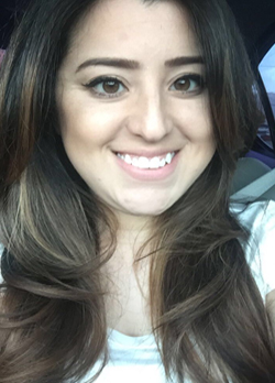 Woman with long, wavy, brown hair wearing a white t-shirt