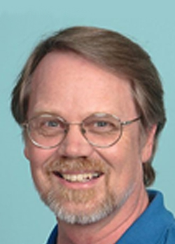 Man with brown hair wearing prescription glasses and a blue polo