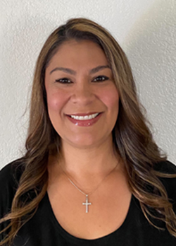 Woman with brown hair wearing a black shirt with golden cross necklace