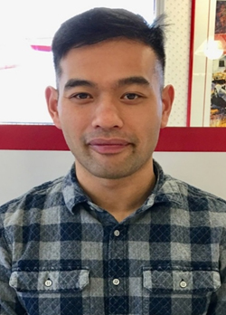 man with short black hair wearing a blue plaid button up shirt