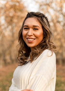 Woman with curly brown hair wearing a white sweater